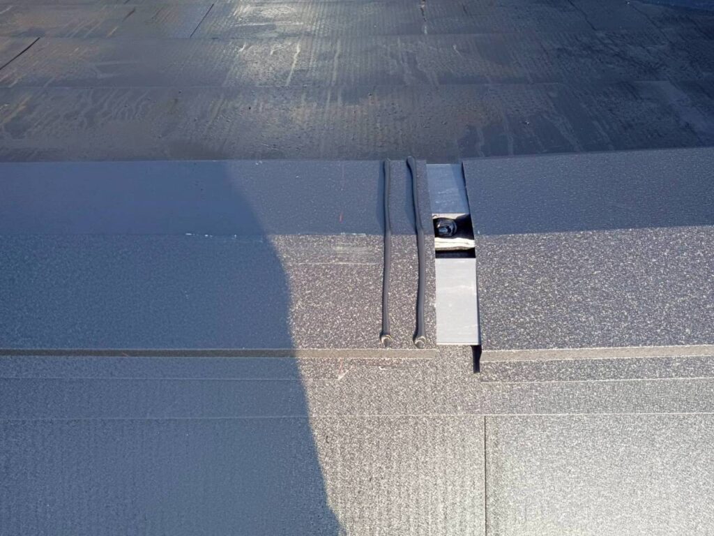 棟包み板金を取付中です。重ね部は雨水が浸入しないように二重コーキングを施工しています。
棟包み板金はステンレスビスにて固定をしています。